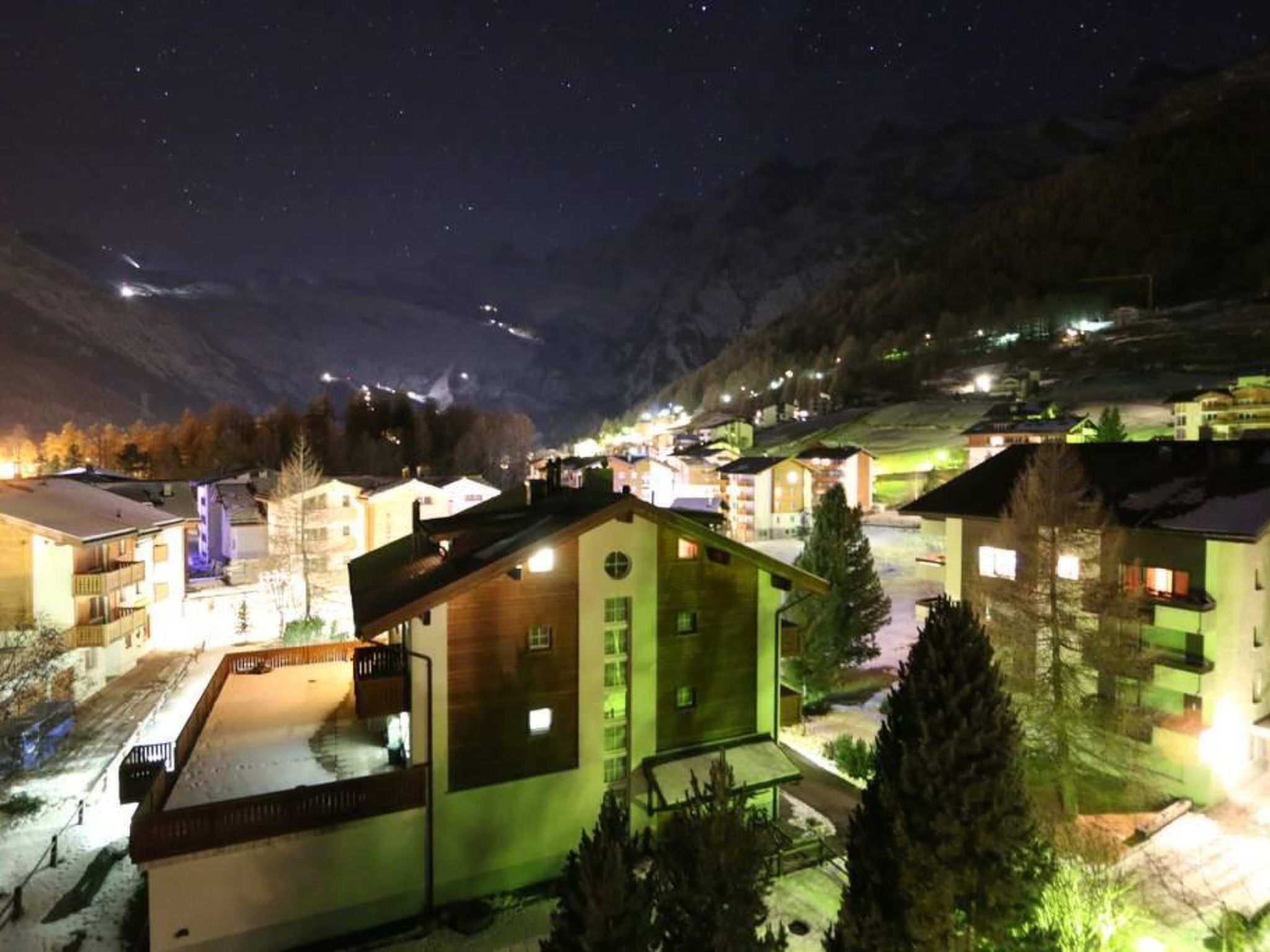 A nighttime view of a village with buildings and a mountain backdrop.