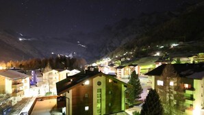 Ein abendlicher Blick auf ein Dorf mit Gebäuden und einem Berg im Hintergrund.
