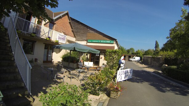 Un bâtiment avec une enseigne indiquant « Auberge L’Avaloir Bar » et une autre indiquant « Auberge à 50 m ».