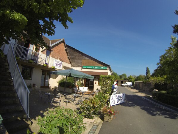 A building with a sign for 'Auberge L'Avaloir Bar' and a sign indicating 'Auberge A 50m'.