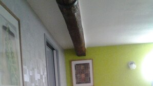 Une pièce avec un mur vert, un tableau encadré, une table ronde avec un vase et deux poubelles.