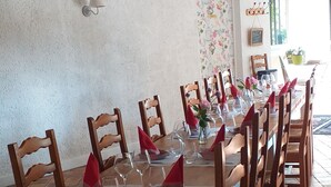 Un espace repas avec une longue table en bois dressée pour un repas, entourée de chaises en bois.