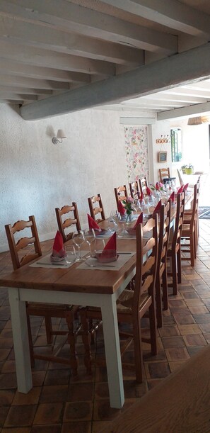 A dining area with a long wooden table set for a meal, surrounded by wooden chairs.