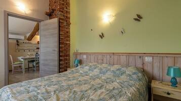 Una camera da letto con un letto, un comodino, una lampada, una parete in mattoni e una decorazione a forma di farfalla.