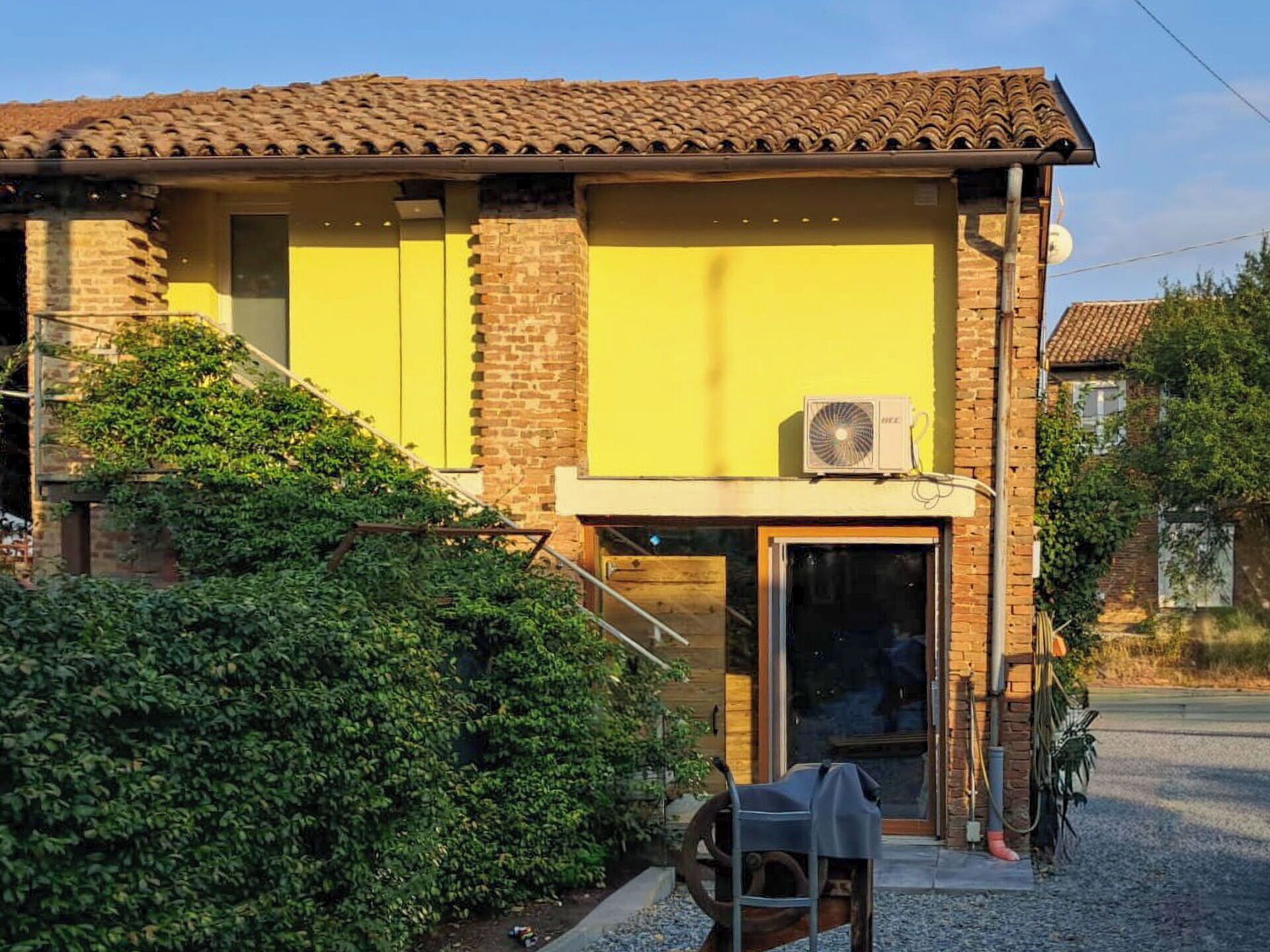 Un edificio con facciata gialla, parte inferiore in mattoni e tetto in tegole.