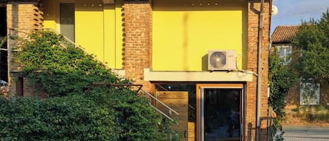 A building with a yellow facade, a brick lower section, and a tiled roof.