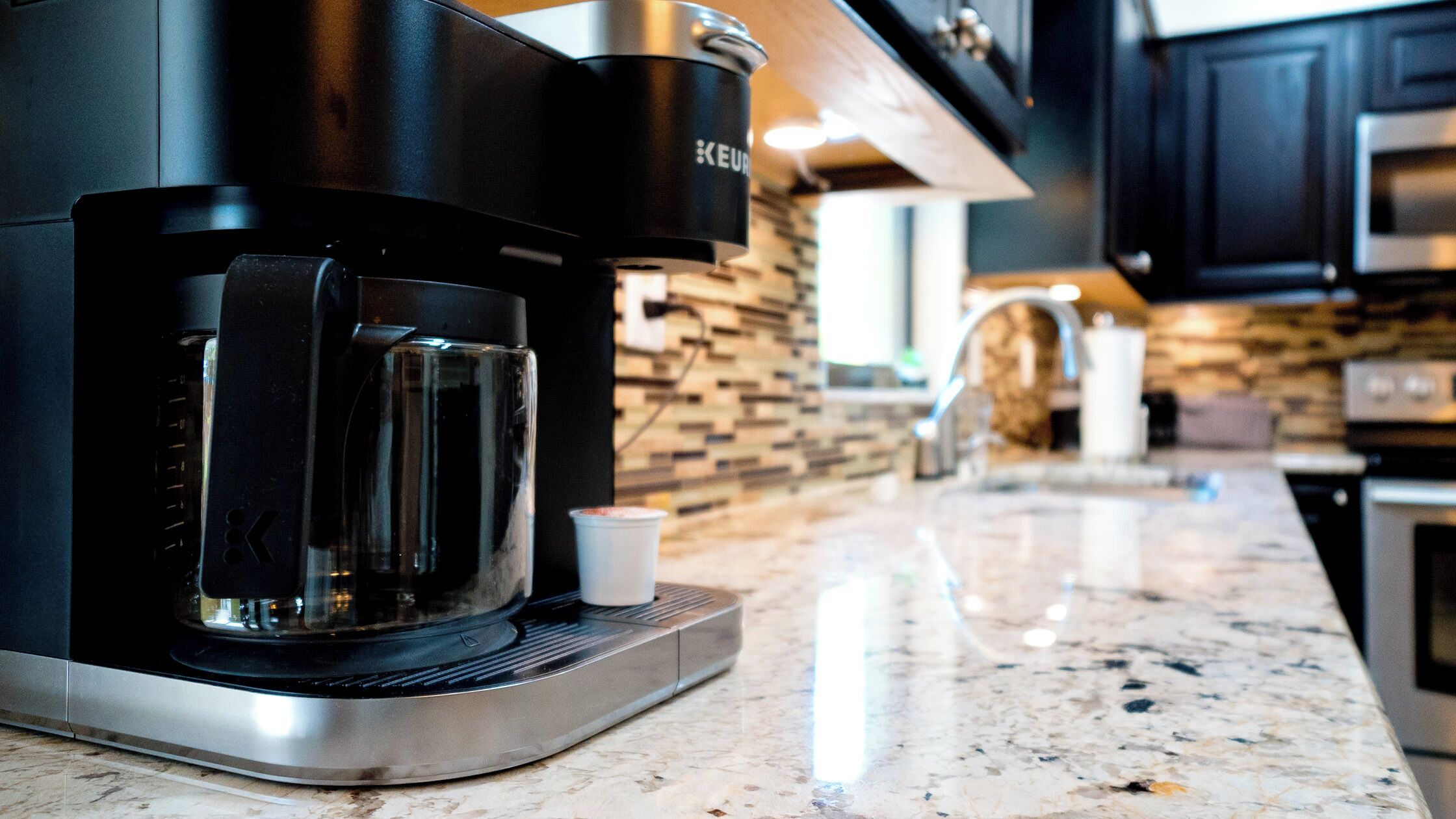 Una cocina moderna con una cafetera Keurig sobre una encimera de granito.