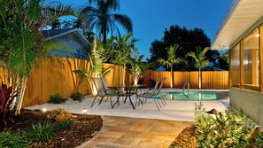 A backyard with a swimming pool, patio furniture, and a wooden fence. - 3-bedroom house in tranquil Bradenton with tropical vibes (Bradenton)