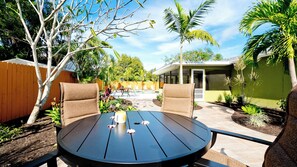 Een achtertuin met een ronde tafel, stoelen, een zwembad en diverse planten.