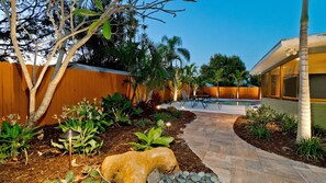 Ein angelegter Garten mit Weg, Pool und Holzzaun.