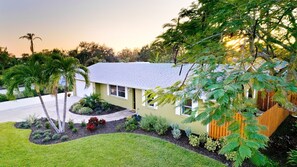 A single-story house with a sloped roof, surrounded by a well-maintained lawn and various shrubs. - 3-bedroom house in tranquil Bradenton with tropical vibes (Bradenton)
