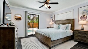 Een slaapkamer met een bed, nachtkastjes, een plafondventilator en uitzicht op de achtertuin.