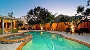 Ein Garten mit Schwimmbecken, Whirlpool und Holzzaun.