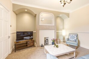 A living room with a television, a fireplace, a sofa, and a chair.