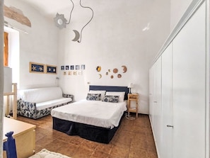 Ein Schlafzimmer mit einem Bett, einem Schlafsofa, einem Kleiderschrank und Wanddekorationen, darunter Sterne und ein Halbmond.
