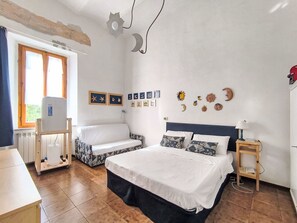 Ein Schlafzimmer mit Bett, einem kleinen Tisch, einer Heizung, einem Fenster und Wanddekorationen.