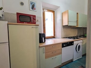 Eine kompakte Küche mit Mikrowelle, Kaffeemaschine, Waschmaschine und einem Fenster mit Blick.