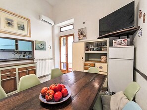 A compact kitchen with a dining table, chairs, a refrigerator, and a television. - Nice apartment for 5 guests with A/C, WIFI and TV (Castiglione Della Pescaia)