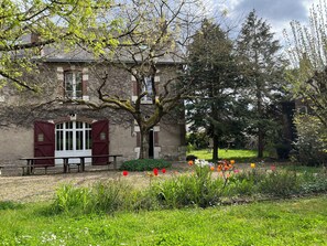 A building with a red door and windows, surrounded by a garden with various plants and flowers. - Large family home on the banks of the Loire River, perfect for cycling and visiting castles (Veuzain-sur-Loire)