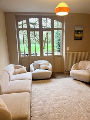 A living room with a large window, a radiator, and a painting on the wall. - Large family home on the banks of the Loire River, perfect for cycling and visiting castles (Veuzain-sur-Loire)