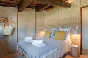 A bedroom with a bed, towels, a hanging basket, and a bedside table. - La Sardagne | Charming House in the Heart of the Garrigue, Near Vallon-Pont-d'Arc (Bourg-Saint-Andéol)