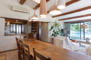 A spacious kitchen with a wooden table and chairs, a built-in wine rack, and a large window overlooking a pool. - La Sardagne | Charming House in the Heart of the Garrigue, Near Vallon-Pont-d'Arc (Bourg-Saint-Andéol)