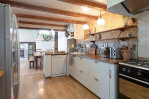 A kitchen with a central island, wooden cabinets, a built-in oven, and a stove. - La Sardagne | Charming House in the Heart of the Garrigue, Near Vallon-Pont-d'Arc (Bourg-Saint-Andéol)
