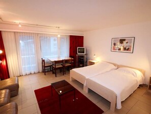 Ein Hotelzimmer mit Bett, Schreibtisch, Stuhl, Fernseher und einem Bild an der Wand.