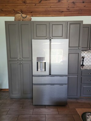 Cocina con refrigerador de acero inoxidable, armarios grises y salpicadero de azulejos.