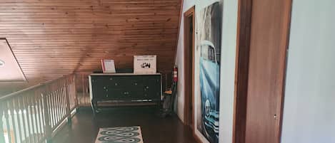 A wooden-floored hallway with a decorative rug, a reception desk, and a wall-mounted light fixture.