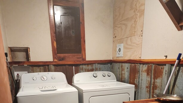 Une buanderie équipée de deux machines à laver à chargement frontal, d’un meuble en bois et d’un paillasson avec un motif textuel.