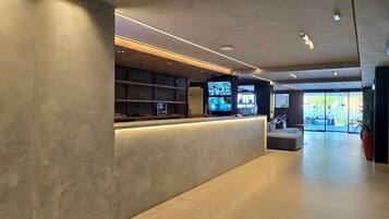 Un área de recepción moderna con mostrador, asientos y vistas al exterior.