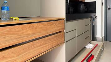 A kitchen with a wooden countertop, a water bottle, a measuring tape, and a red broom.