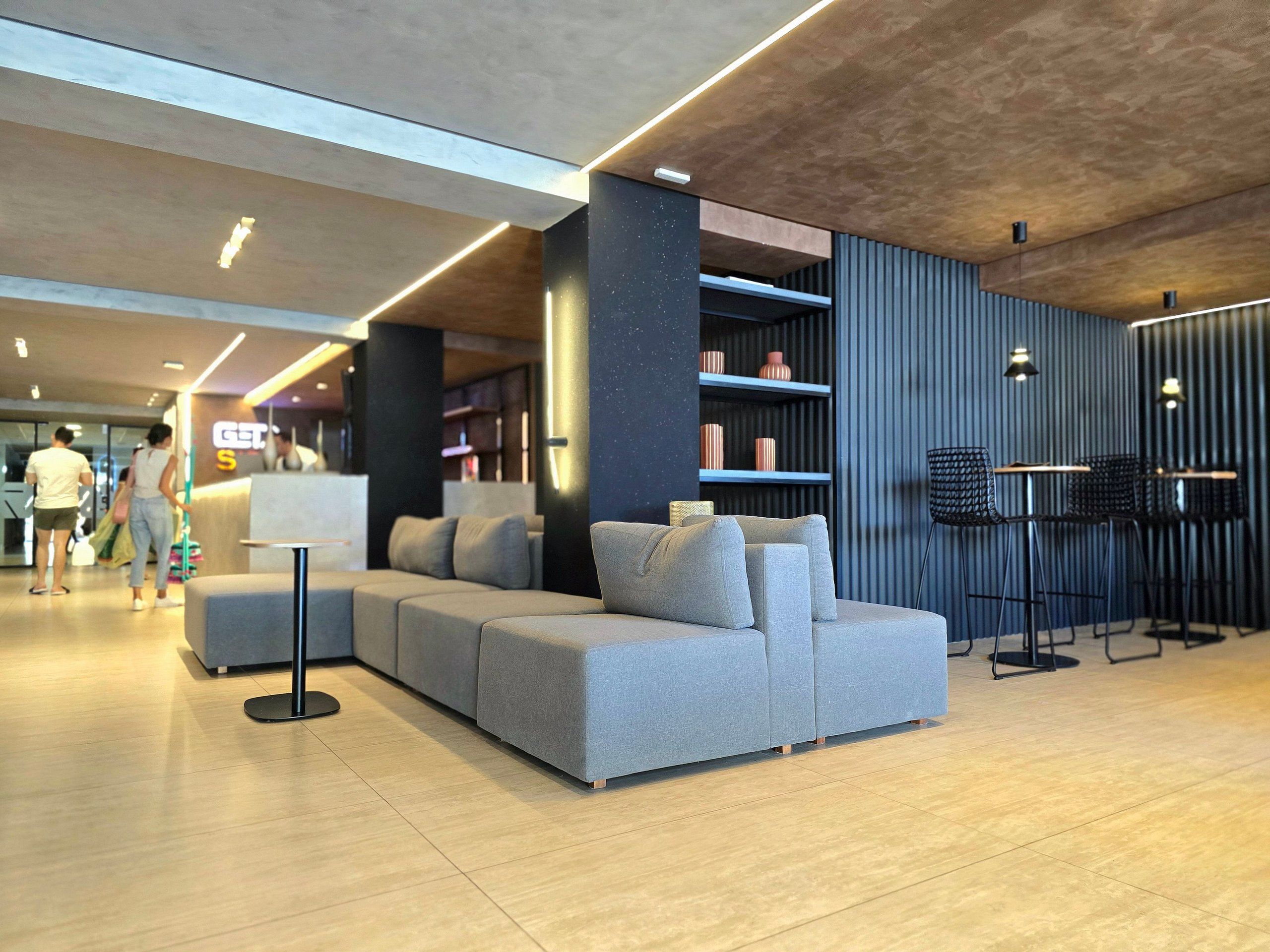 Uma área de estar moderna com um sofá seccional, um balcão com banquetas e uma estante de livros.