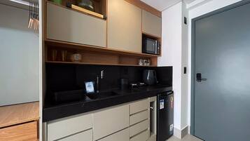 Cocina compacta equipada con microondas, cafetera y refrigerador.