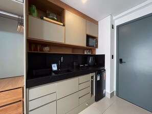 Eine kleine Küche mit Mikrowelle, Kaffeemaschine und Kühlschrank.
