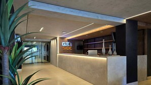 Un área de recepción moderna con un mostrador, un cartel que dice 'GT BY SIDE' y una planta en maceta.