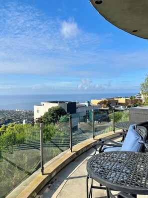A terrace with a table and chairs, overlooking a coastal cityscape. - Spacious 4-bedroom house in Laguna Beach (Laguna Beach)
