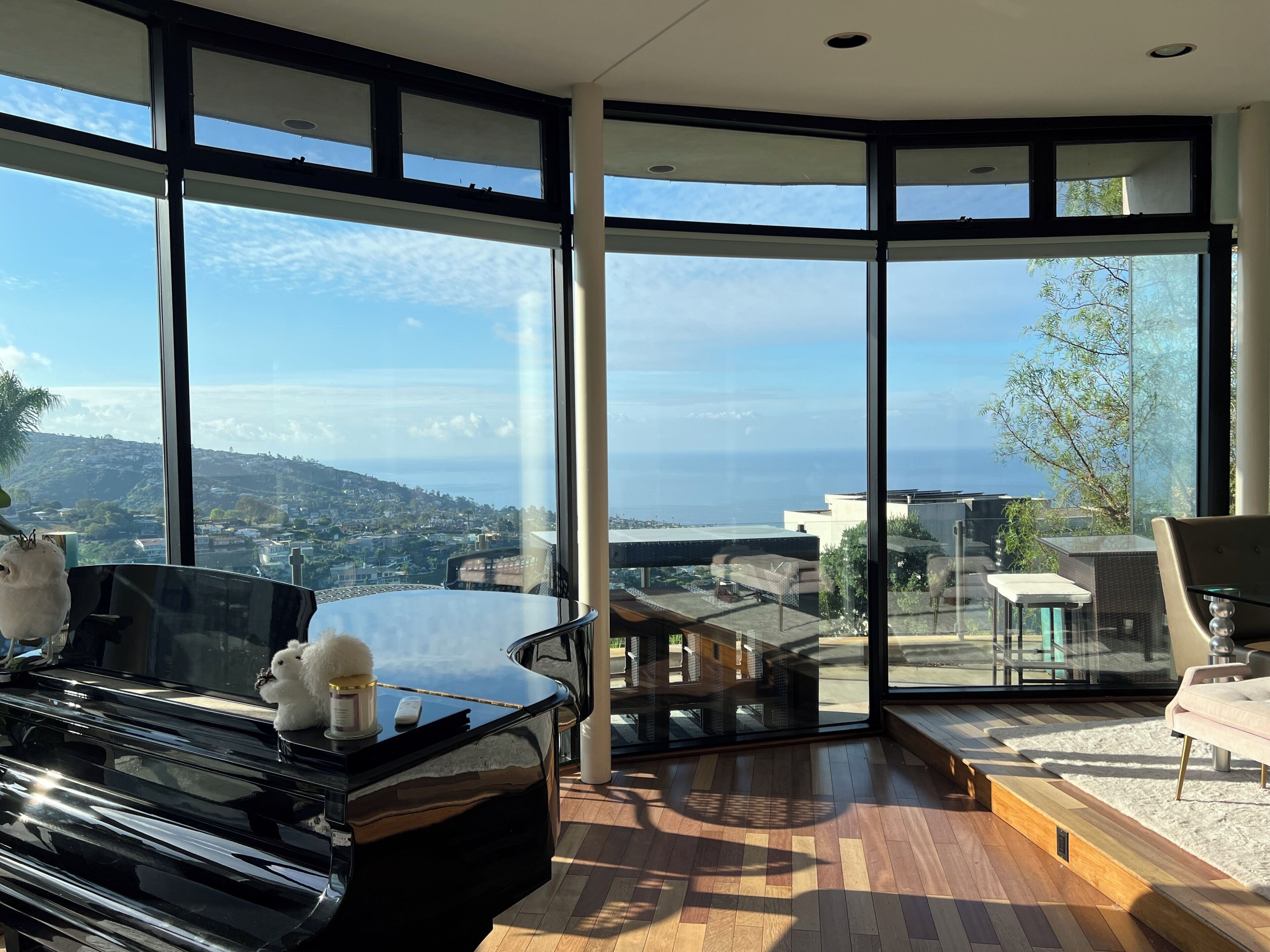 A modern interior with large windows, a piano, and a view of the sea.