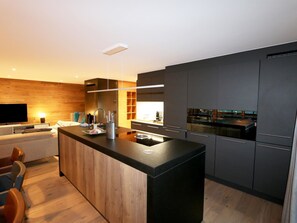 A modern kitchen with a central island, dark cabinetry, and a built-in oven. - Derby Appartement/Fewo Derby 1 by Interhome (Saas-Fee)