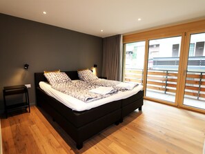 A modern bedroom with a large bed, wooden flooring, and a sliding glass door leading to an outdoor area. - Derby Appartement/Fewo Derby 1 by Interhome (Saas-Fee)