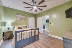 A bedroom with a bed, nightstand, lamp, ceiling fan, and a painting on the wall. - Blue Haven in Erwin, TN (Erwin)