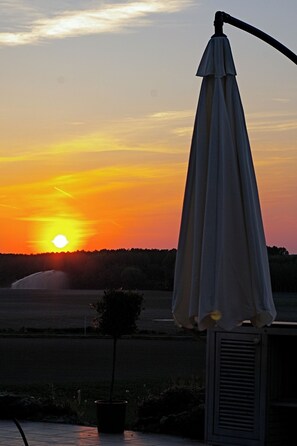 A sunset with a visible sun, a potted plant, and a white umbrella. - La Gloriette a splendidly light, spacious and comfortable gîte for 2. (Les Bois d'Anjou)