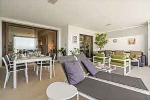 Un espace de vie moderne comprenant une table à manger pour six personnes, un coin salon avec deux fauteuils et un canapé.