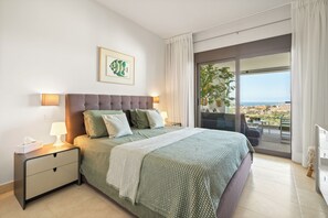 Ein Schlafzimmer mit Bett, Nachttisch, Lampe und Blick ins Freie.