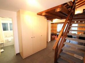 A spacious room with a wooden staircase, a wardrobe, and a dining area with a table and chairs. - Sarazena Appartement/Fewo 4-Bettwohnung U by Interhome (Saas-Fee)