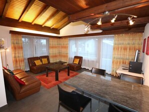 A modern living room with a glass-top coffee table, leather sofas, and a dining area with a glass table. - Sarazena Appartement/Fewo 4-Bettwohnung U by Interhome (Saas-Fee)