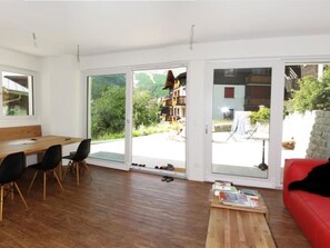 Ein stilvolles Wohnzimmer mit Esstisch aus Holz, schwarzen Stühlen, einem roten Sofa und einem Couchtisch aus Holz.