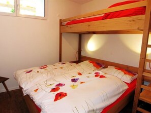 Ein Stockbett mit weißer Matratze und farbenfroher Blumenwäsche.