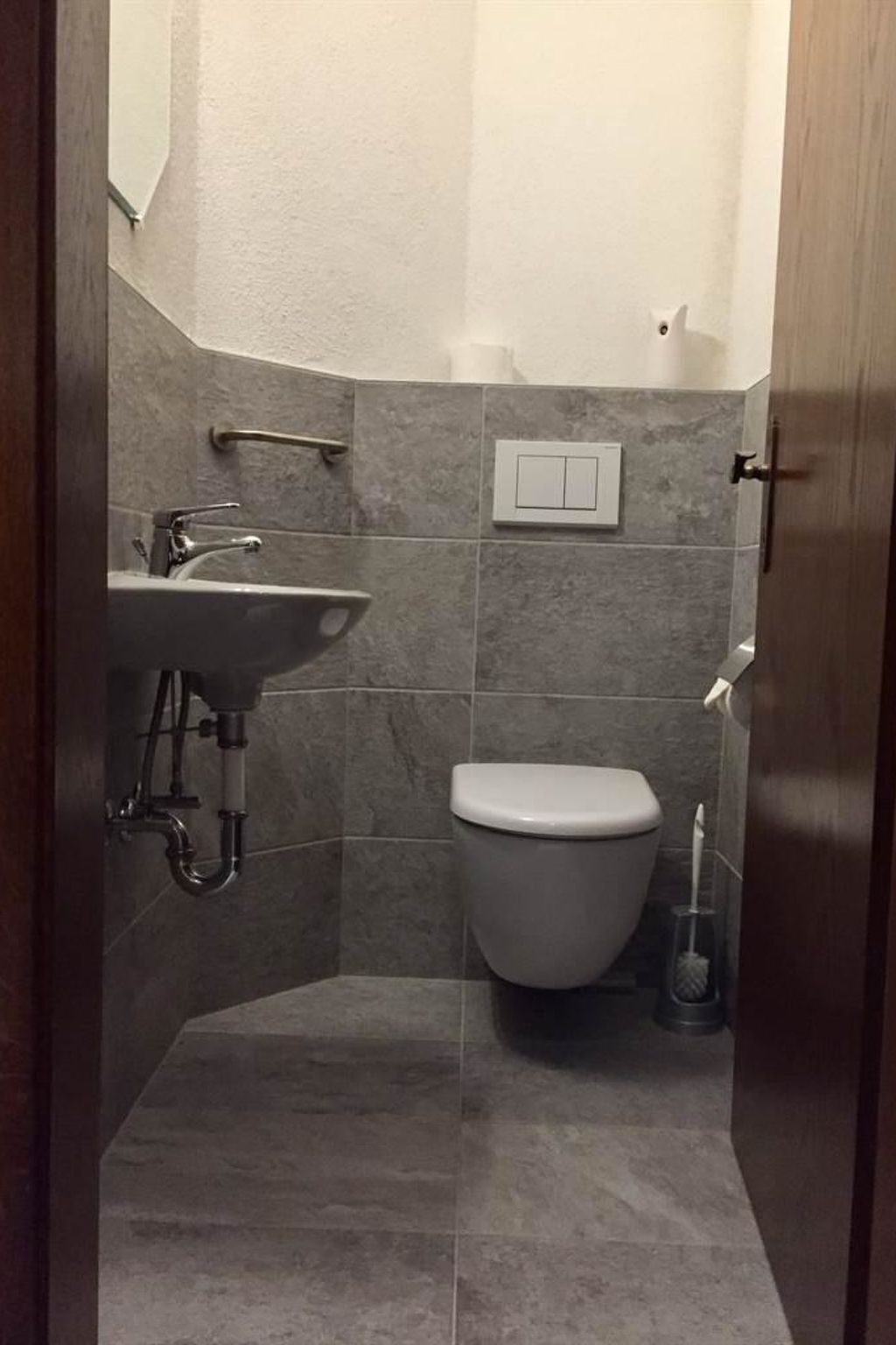 A small bathroom with a sink, toilet, and a handrail.